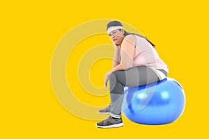 Overweight Asian woman sitting on a gym ball looking bored