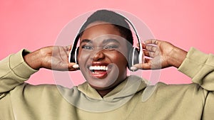 Overweight Black Woman Listening To Music Wearing Headphones, Pink Background