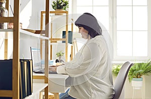 Overweight brunette woman working with laptop in office