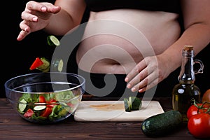 Overweight fat woman dropping some vegetable slices to bowl with
