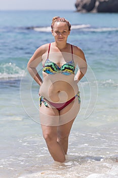 Overweight female person in bikini posing with arms akimbo photo