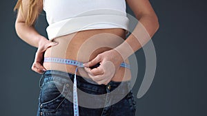 Overweight Female woman measuring her waist with a measuring tape. She was disappointed at her complete figure