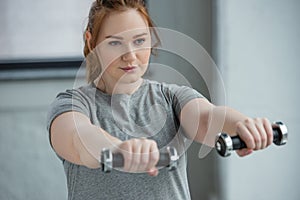 Overweight girl exercising with dumbbells