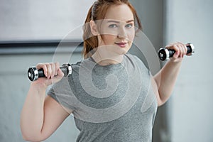 Overweight girl lifting dumbbells