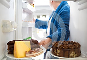 Overweight guy take sausage and cheese from fridge