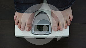 Overweight male feet on weighing scales, measuring kilograms after workout