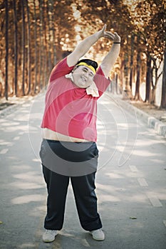 Overweight man doing warm-up his arms at park