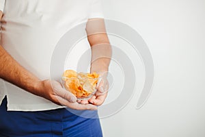Overweight man eating fattening potato chips