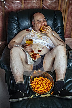 Overweight man eating and watching TV