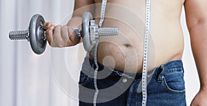 Overweight man exercising by lifting weight with a dumbbell