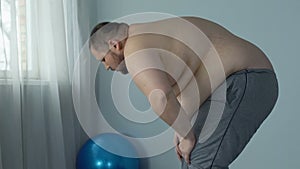 Overweight man feeling fatigue and breath disorder during home workout, dyspnea