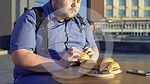 Overweight man holding hamburger, unhealthy nutrition, junk food, lifestyle