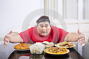 Overweight man hugging at a lot of unhealthy food