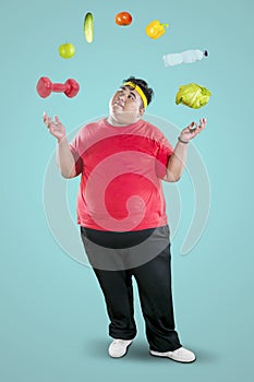 Overweight man juggling dumbbell and foodstuff