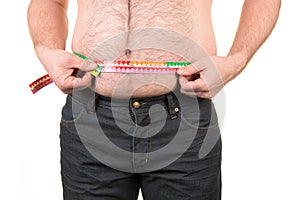 Overweight man measuring belly fat with measure tape