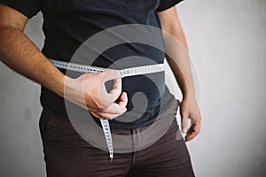 Overweight man measuring waist with measure tape