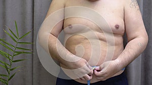 Overweight Man Measuring Waist with Tape Measure