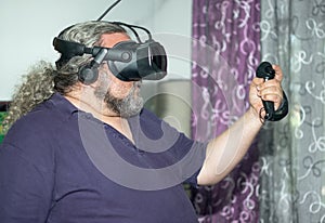 Overweight man playing virtual reality raising hands with joysticks at VR