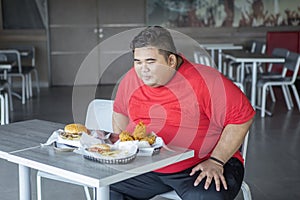 Overweight man ready to eat fast food in cafe