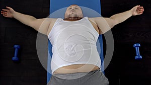 Overweight man resting on floor after exhausted exercise, genetic predisposition