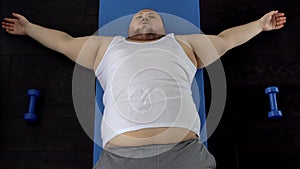 Overweight man resting on floor after exhausted exercise, genetic predisposition photo
