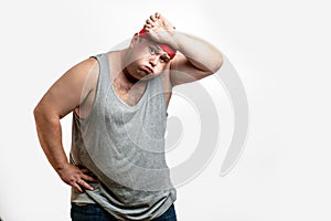 Overweight man resting, tired after training, with hand on forehead against white