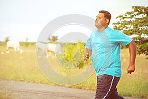 Overweight man running on road - concept of fat man fitness - obese person jogging to reduce the weight.