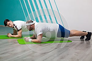 An overweight man is stressed to the limit while standing in the bar during fitness group classes