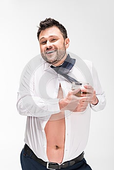 Overweight man in tight shirt looking at camera and holding glass of beer on white