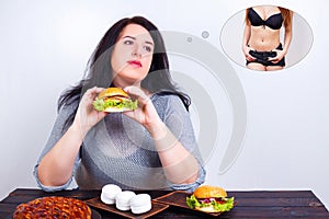 Overweight obese woman eating hamburger and dreaming of fit and