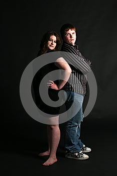Overweight teenage couple standing back to