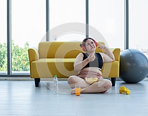 Overweight woman and asian girl enjoy eating food on sofa at home