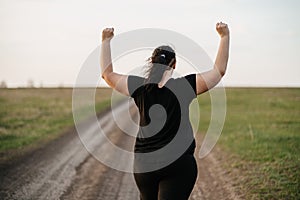 Overweight woman celebrating rising hands to sky