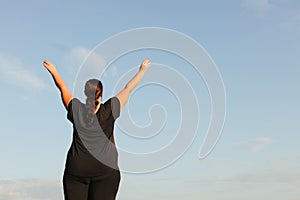 Overweight woman celebrating rising hands to sky