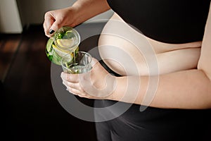Overweight woman drinking infused water. Detox