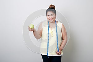 Overweight woman eating food on gray background