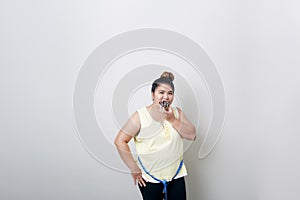 Overweight woman eating food on gray background