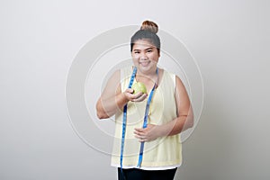 Overweight woman eating food on gray background