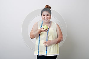 Overweight woman eating food on gray background