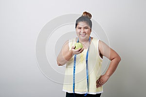 Overweight woman eating food on gray background