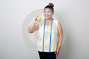 Overweight woman eating food on gray background