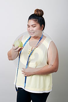 Overweight woman eating food on gray background