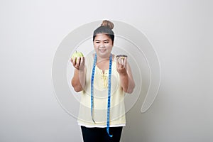 Overweight woman eating food on gray background