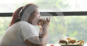Overweight woman eating hamburger in restaurant