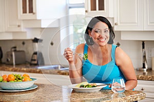 Overweight Woman Eating Healthy Meal in Kitchen