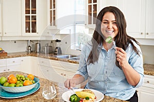 Overweight Woman Eating Healthy Meal In Kitchen photo