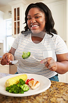 Overweight Woman Eating Healthy Meal in Kitchen