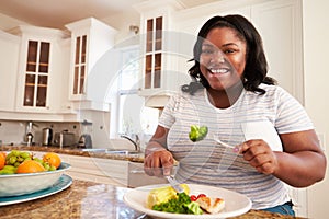 Overweight Woman Eating Healthy Meal in Kitchen photo