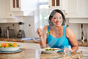 Overweight Woman Eating Healthy Meal in Kitchen photo