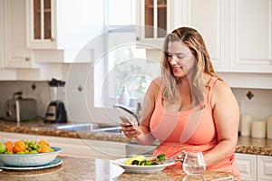 Overweight Woman Eating Healthy Meal And Using Mobile Phone